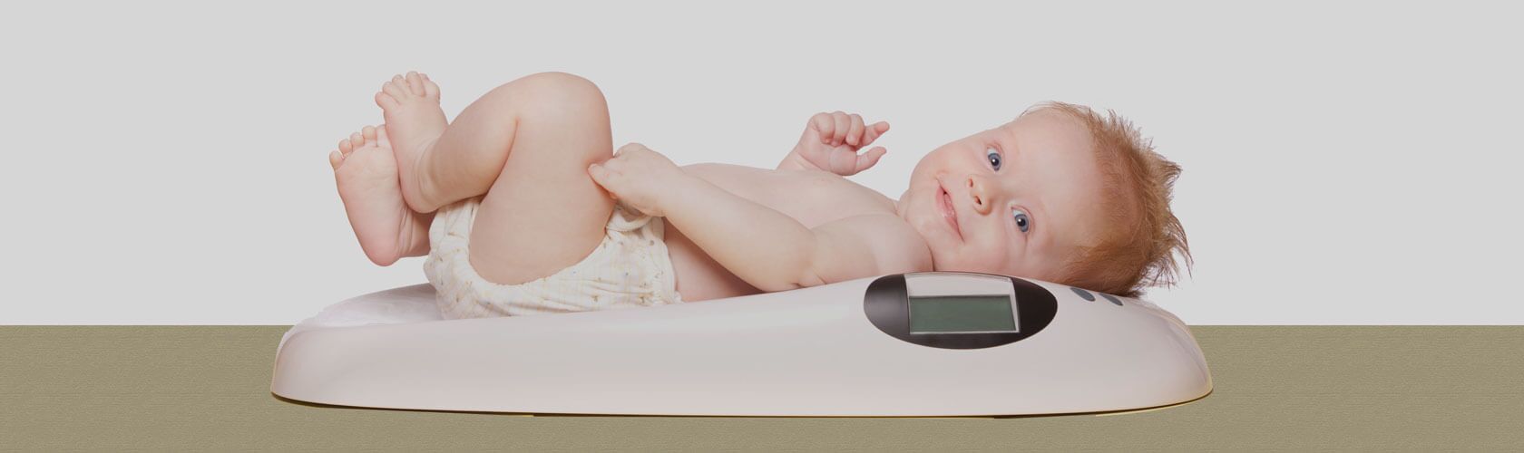Ein lächelndes Baby liegt auf einer digitalen Babywaage in einer Apotheke.