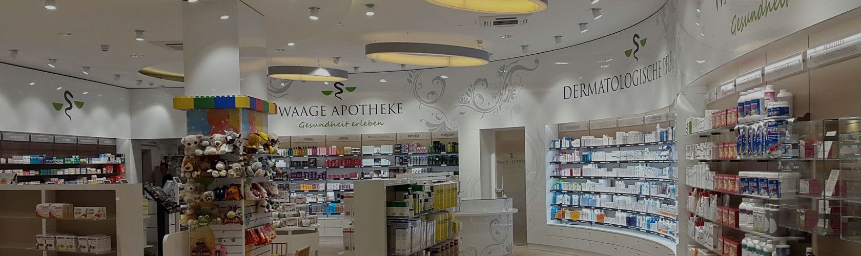 Eine moderne Apotheke mit zahlreichen Regalen voller Medikamente und einer bunten Spielzeugauslage im Vordergrund.