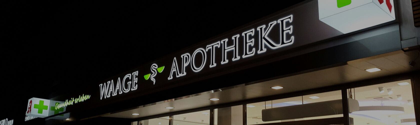 Die beleuchtete Außenansicht der Waage-Apotheke in Berlin bei Nacht zeigt ein einladendes Geschäftsumfeld.